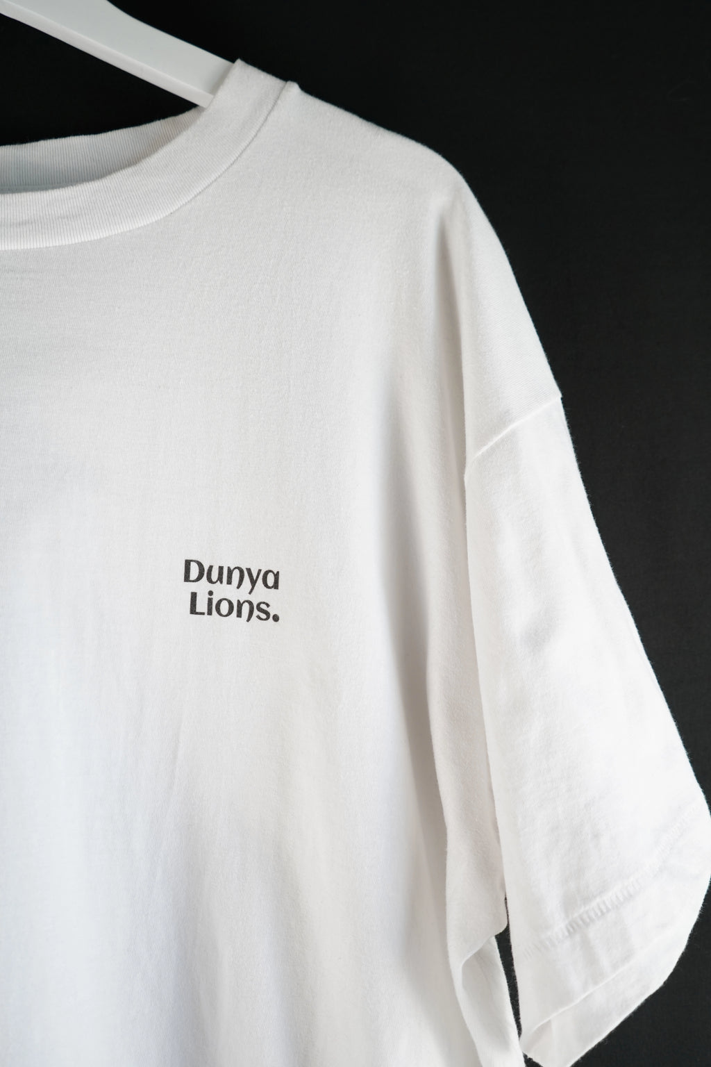 Side view of white oversized T-shirt with minimalist chest logo.