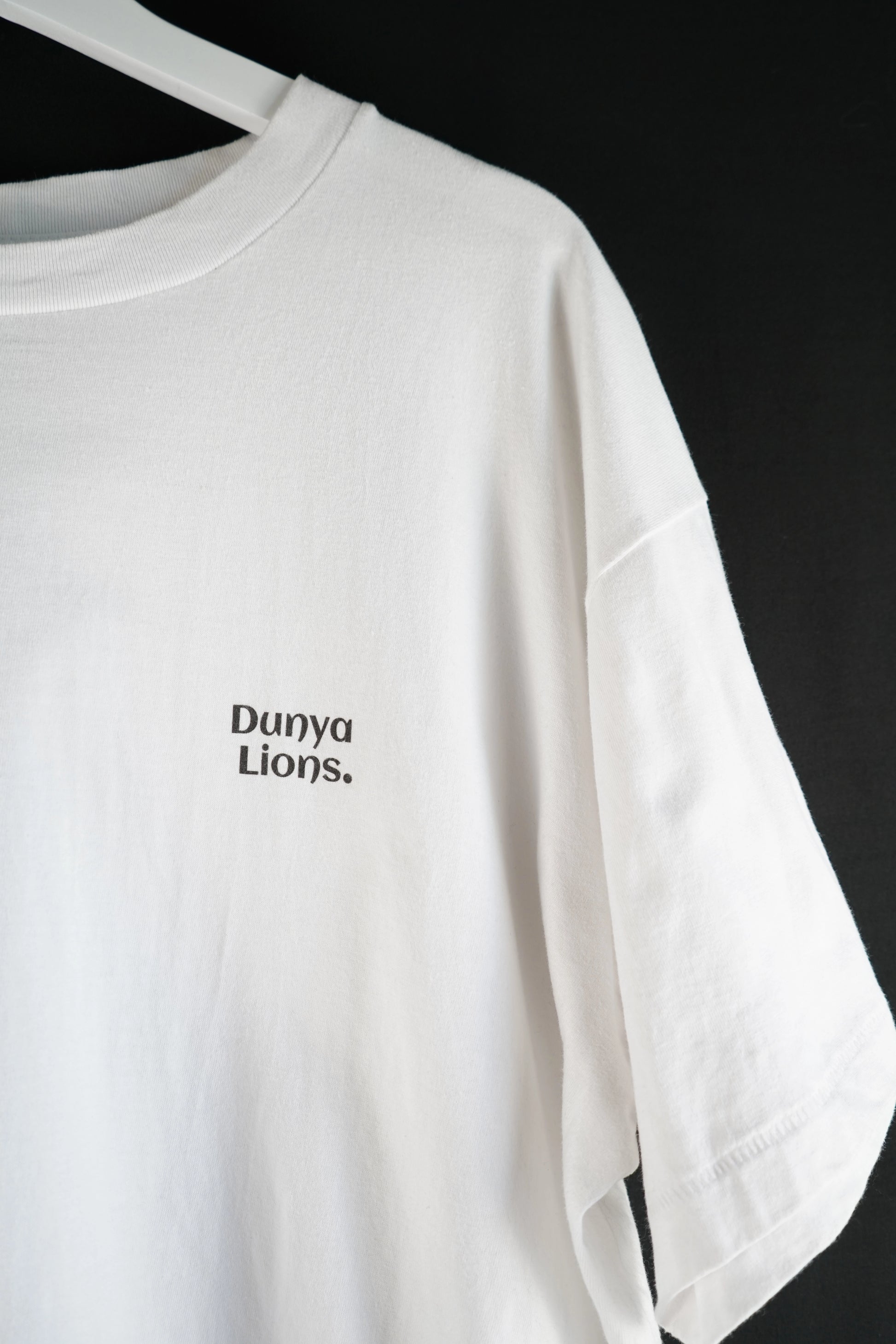 Side view of white oversized T-shirt with minimalist chest logo.
