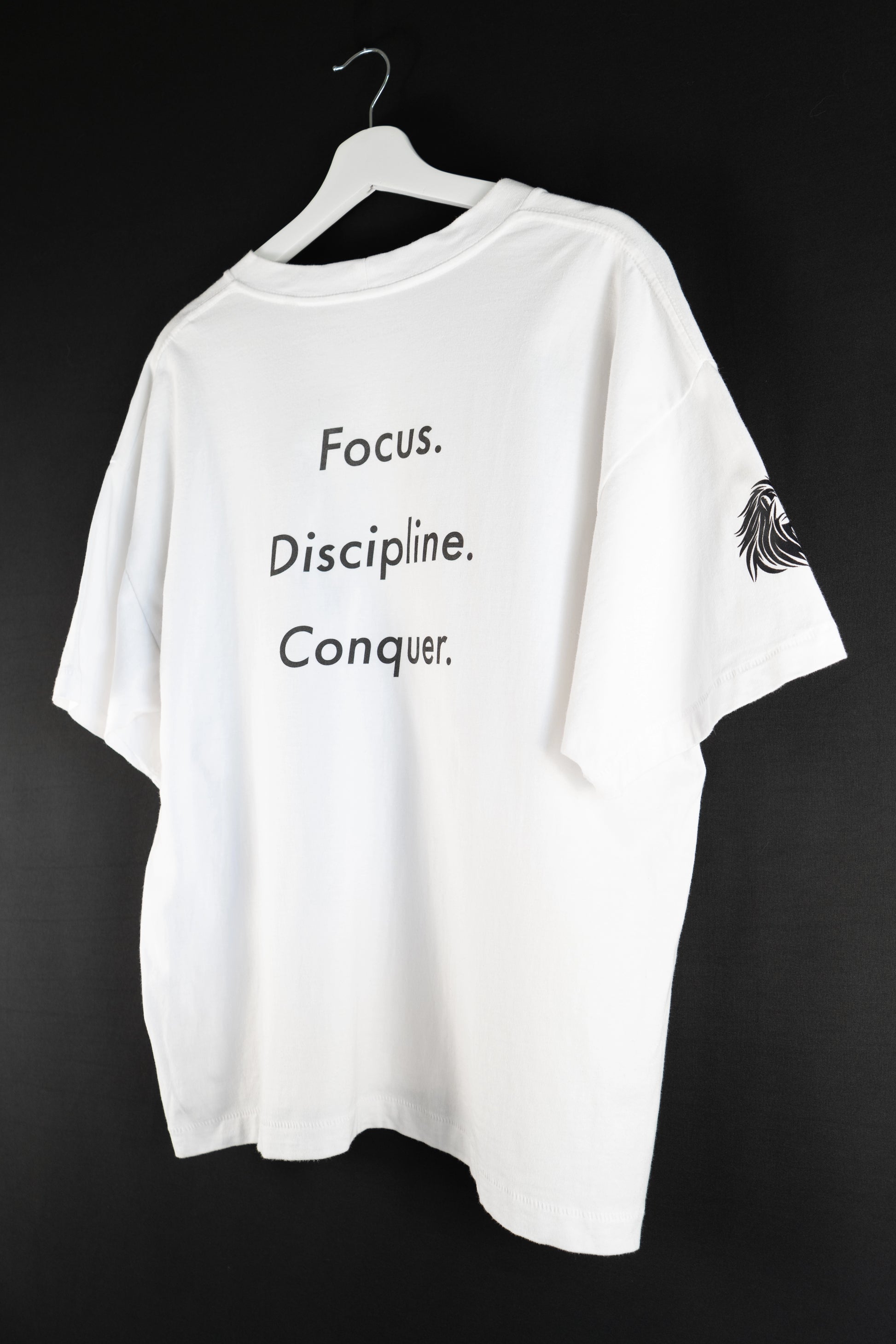 White oversized T-shirt with large back print reading “Focus. Discipline. Conquer.” in black text.