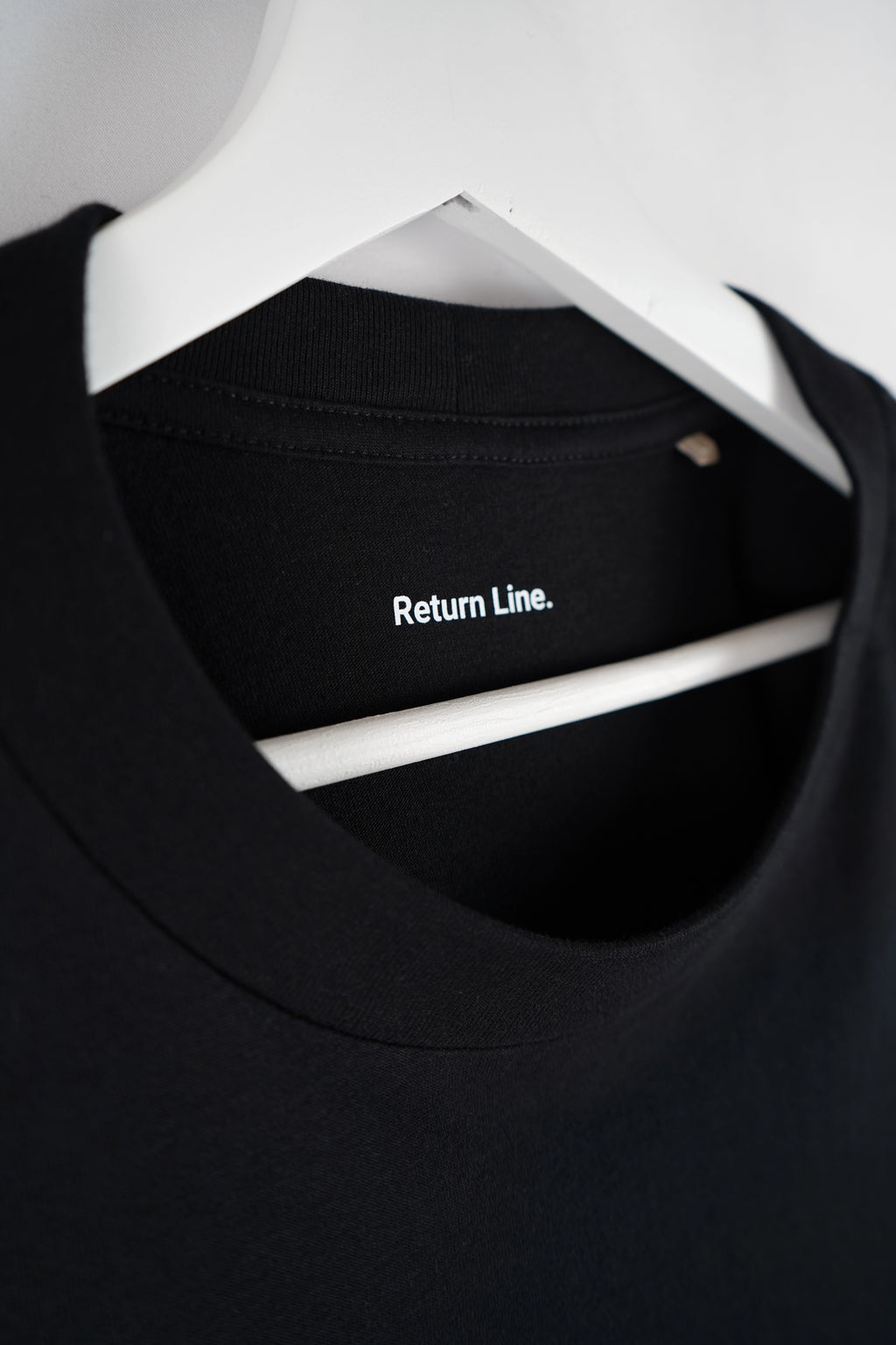 Innenseitiger Schriftzug „Return Line.“ im Nackenbereich des Shirts.