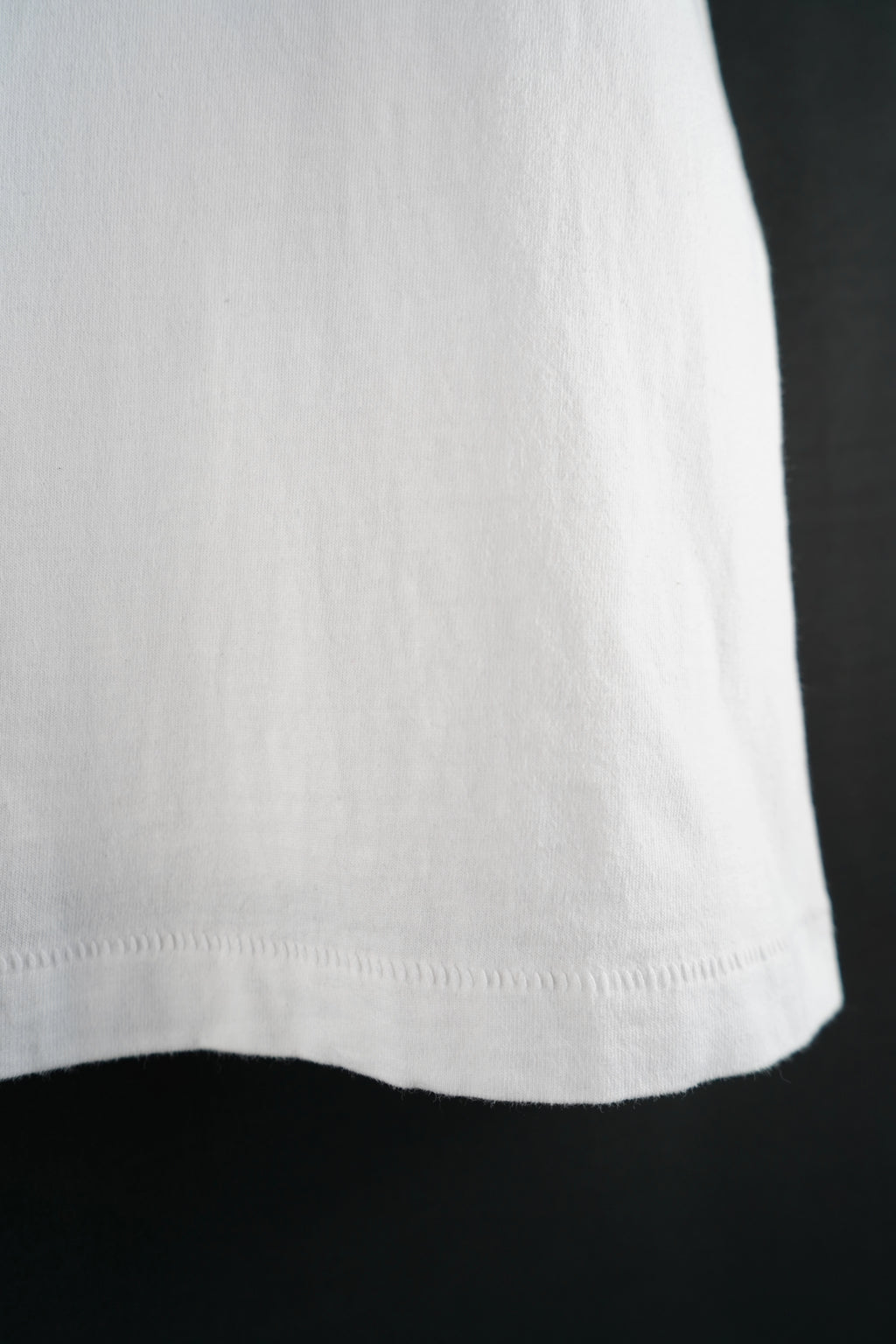 Close-up of the hem of a white oversized T-shirt, minimalist streetwear design by Dunya Lions.